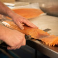 Fresh salmon being sliced on a work surface during food preparation.