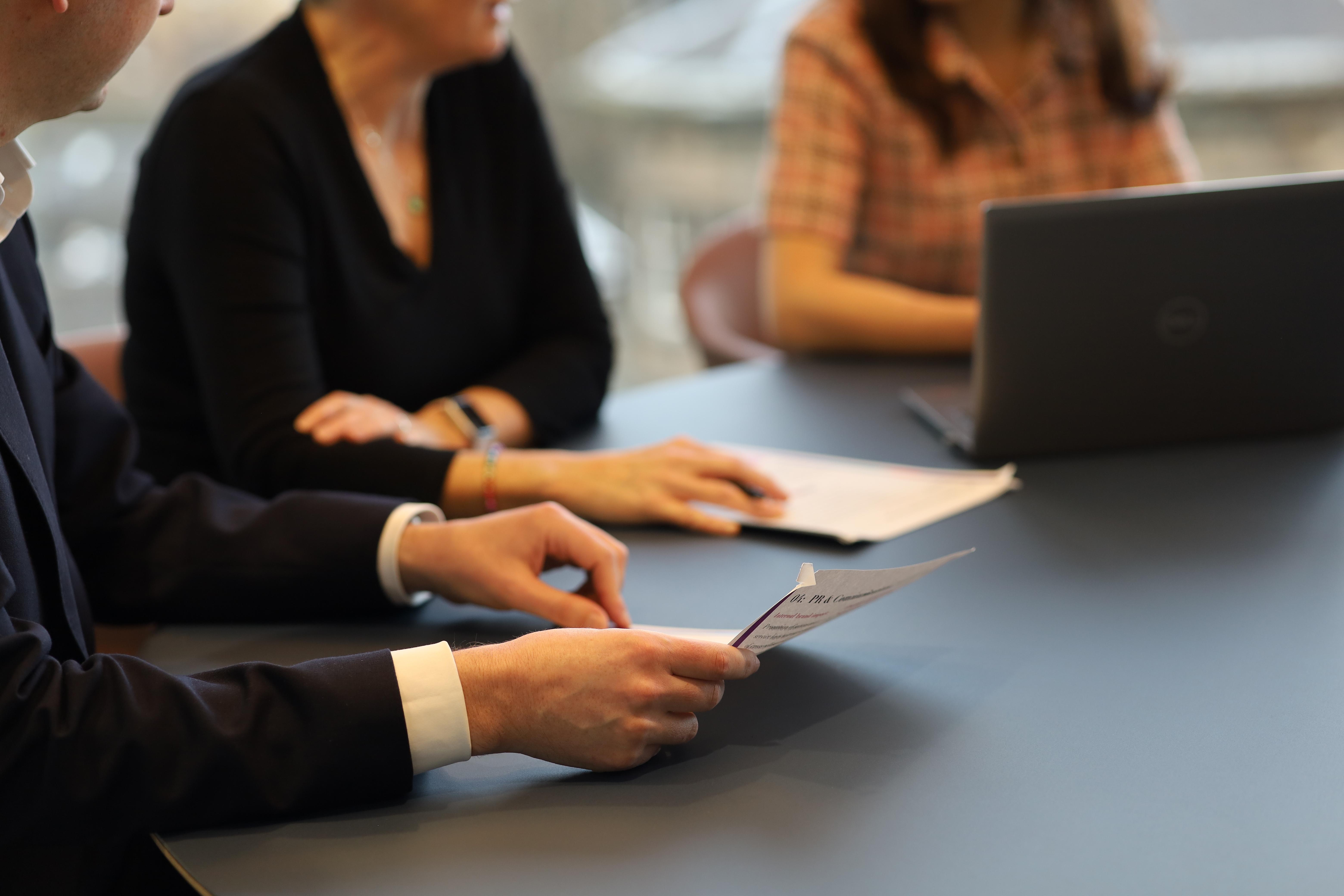 Business professionals reviewing documents during a boardroom-style meeting on corporate decision-making and governance.