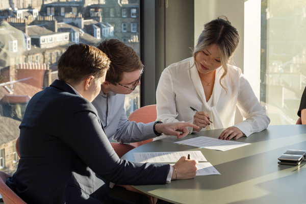 Professionals reviewing workplace documents during a meeting in a modern office, reflecting employee relations, compliance and organisational policy planning.