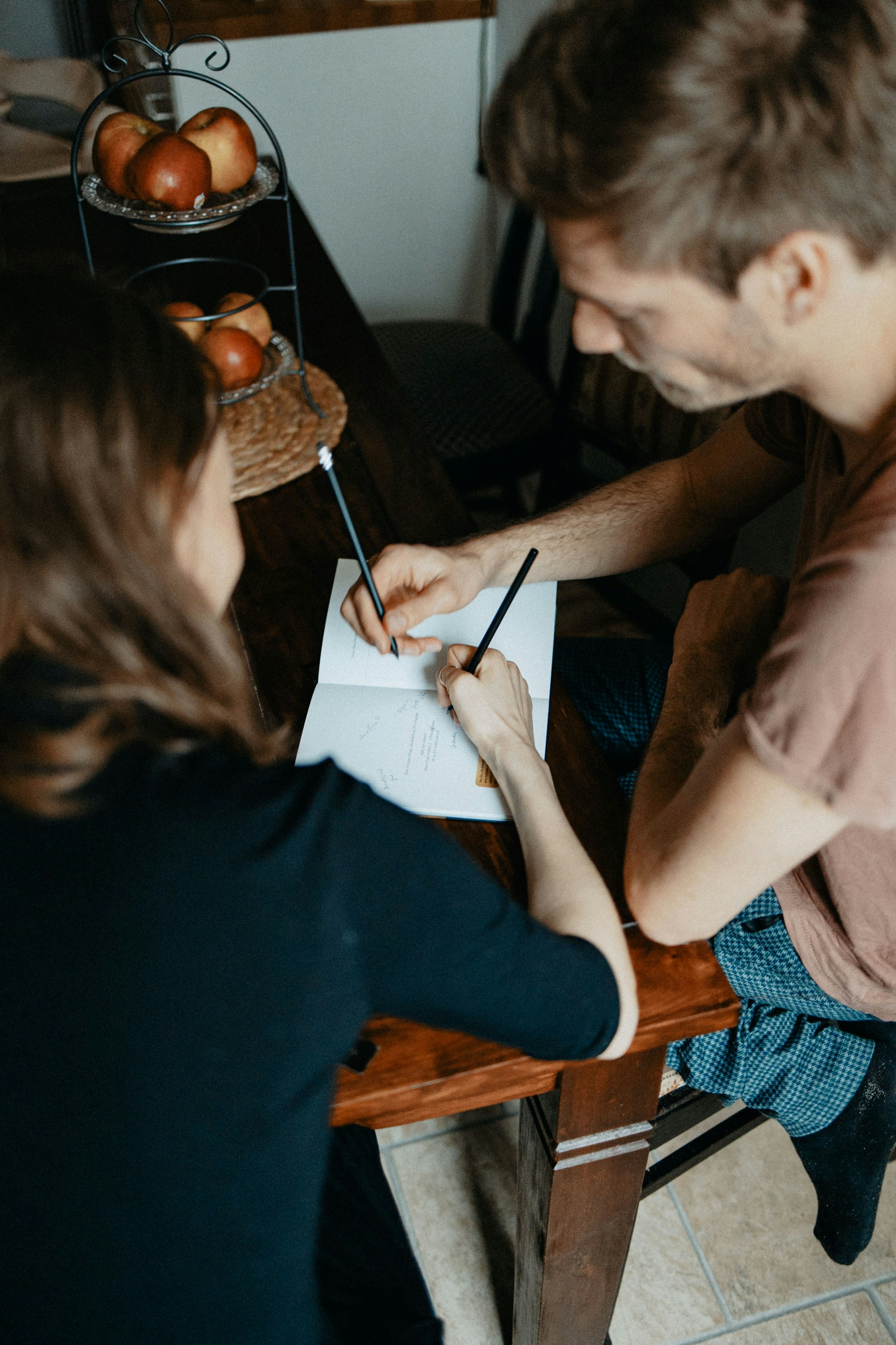 Two people reviewing and signing documents at a table, illustrating legal and financial arrangements following a relationship breakdown.