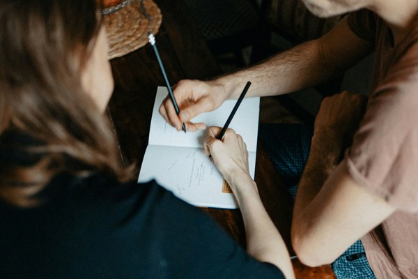 Two people reviewing and signing documents at a table, illustrating legal and financial arrangements following a relationship breakdown.