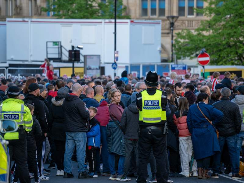 Police officers monitoring a large crowd outside a public venue, illustrating public safety and security considerations at busy events.