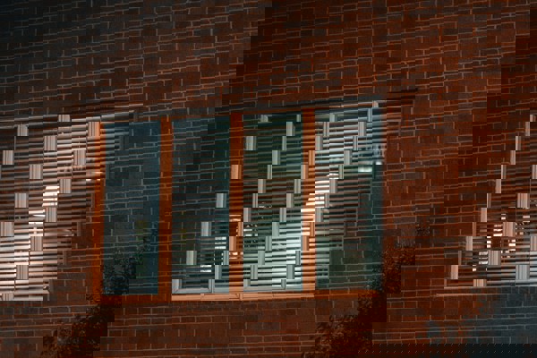 Exterior view of a brick office building at night, showing illuminated windows with blinds partially open.