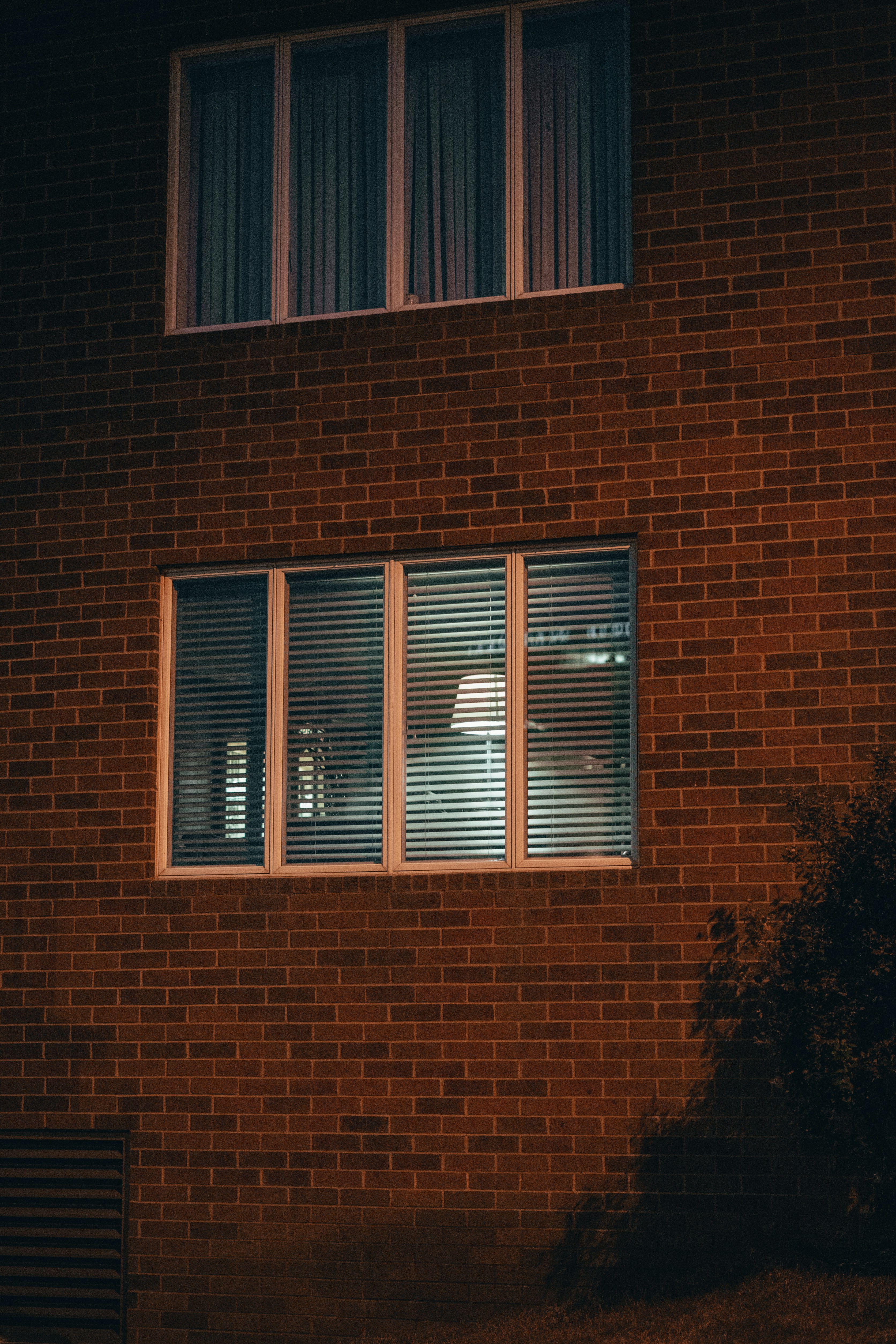 Exterior view of a brick office building at night, showing illuminated windows with blinds partially open.