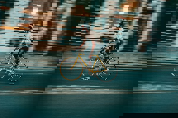 A person cycling on a city street without a helmet, illustrating a scenario where road safety practices may be relevant to negligence considerations.