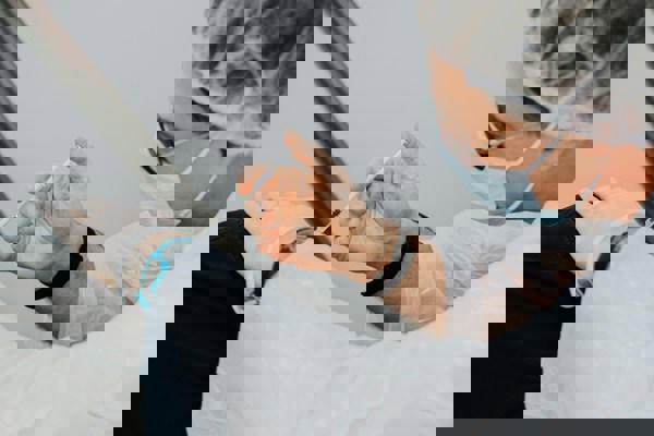 Practitioner administering a cosmetic injection in a clinical setting using protective gloves and mask.