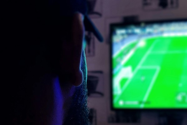 Person watching a football match on a television screen at home