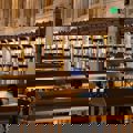 People seated at desks in a large library, studying and working among shelves of books in a formal academic setting.