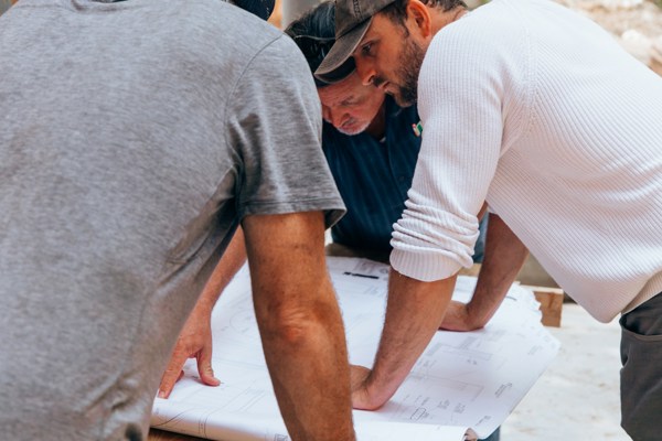 Construction professionals reviewing building plans together on a construction site.