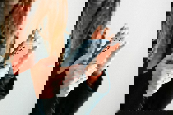 Person holding and using a smartphone against a neutral background.