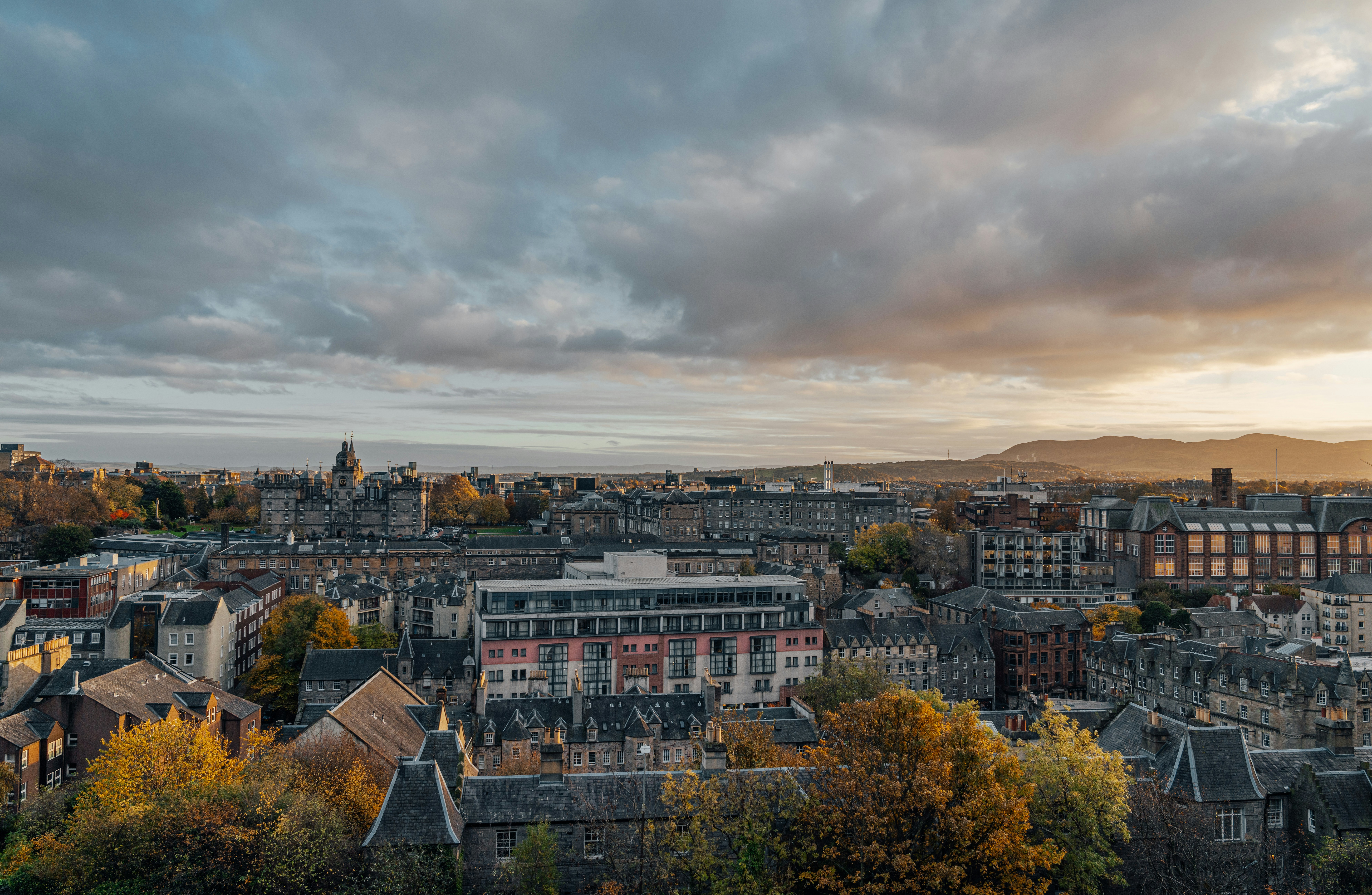 Edinburgh cityscape with historic and modern buildings beneath a cloudy sky.