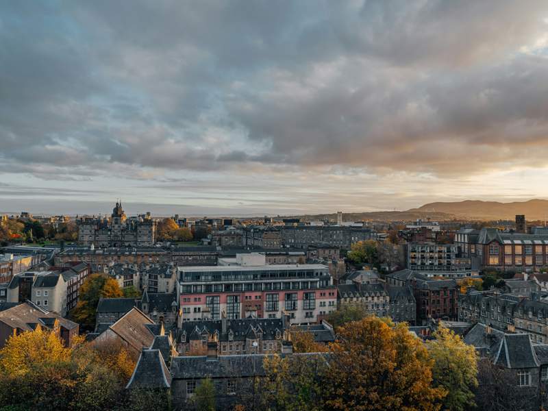Edinburgh cityscape with historic and modern buildings beneath a cloudy sky.