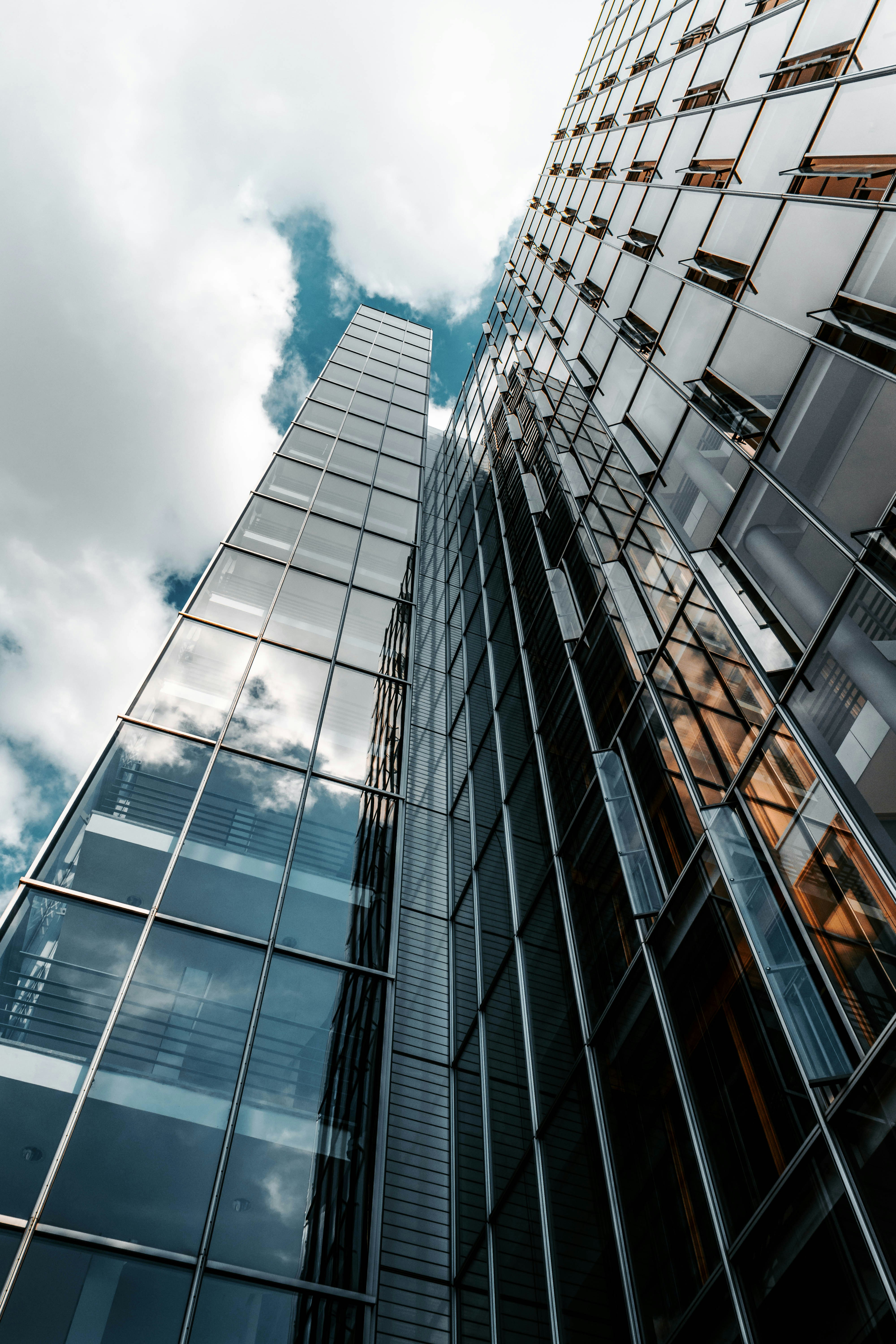 View looking up at modern glass office buildings against a cloudy sky, representing contemporary business and commercial settings.