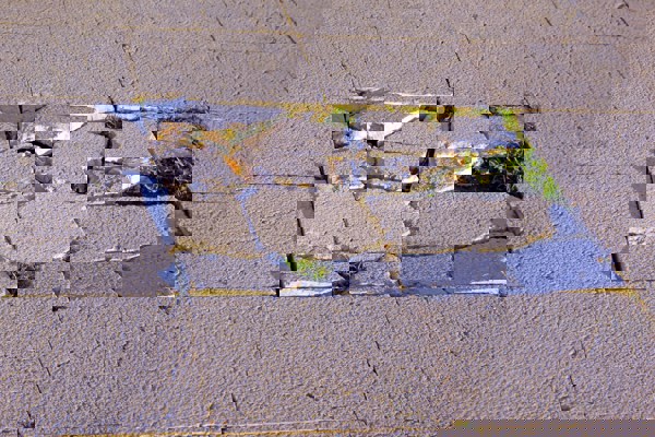 Broken and uneven paving slabs creating a trip hazard on a public pavement.