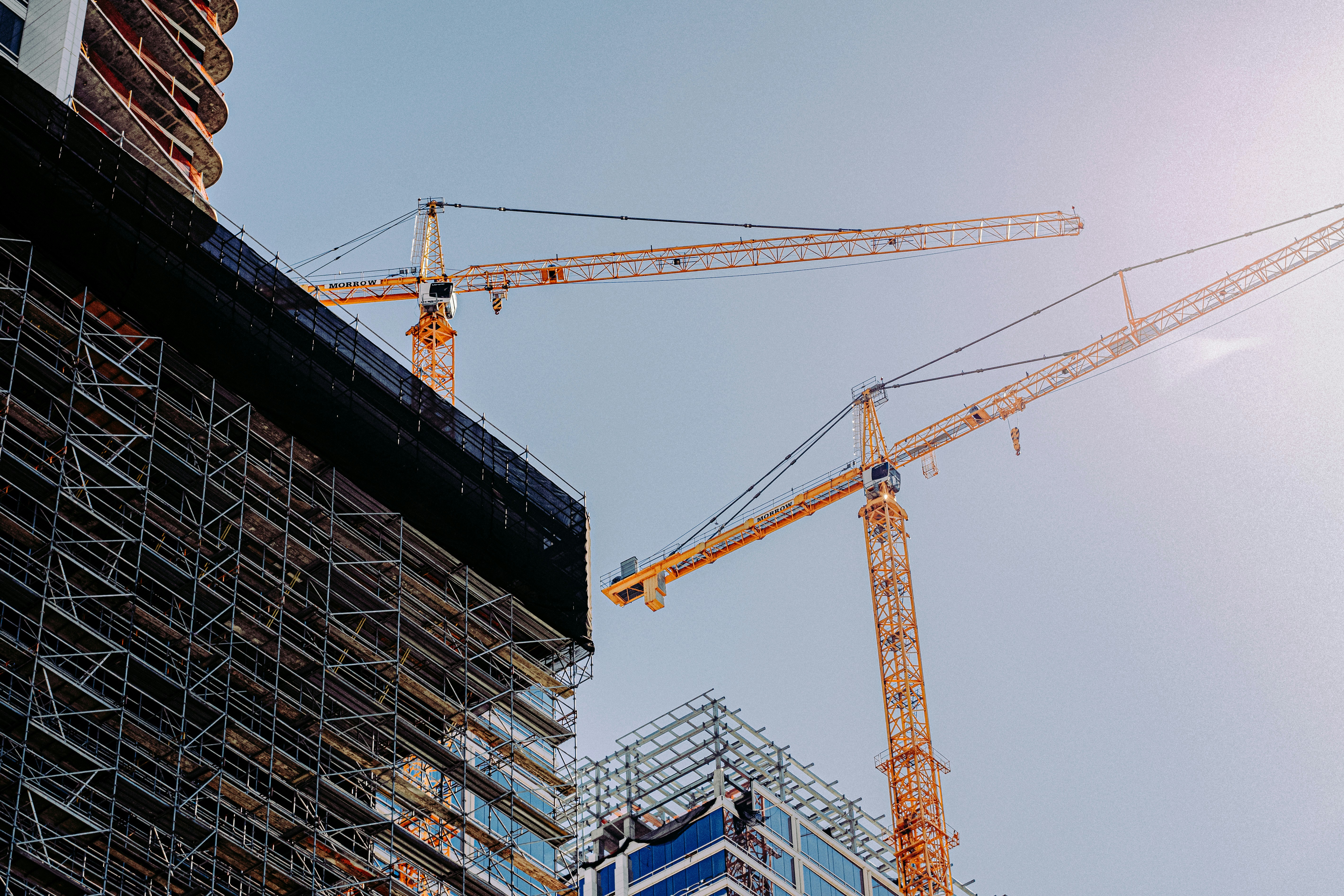 Tower cranes and scaffolding around a large construction project, illustrating the construction sector and project delivery risks.