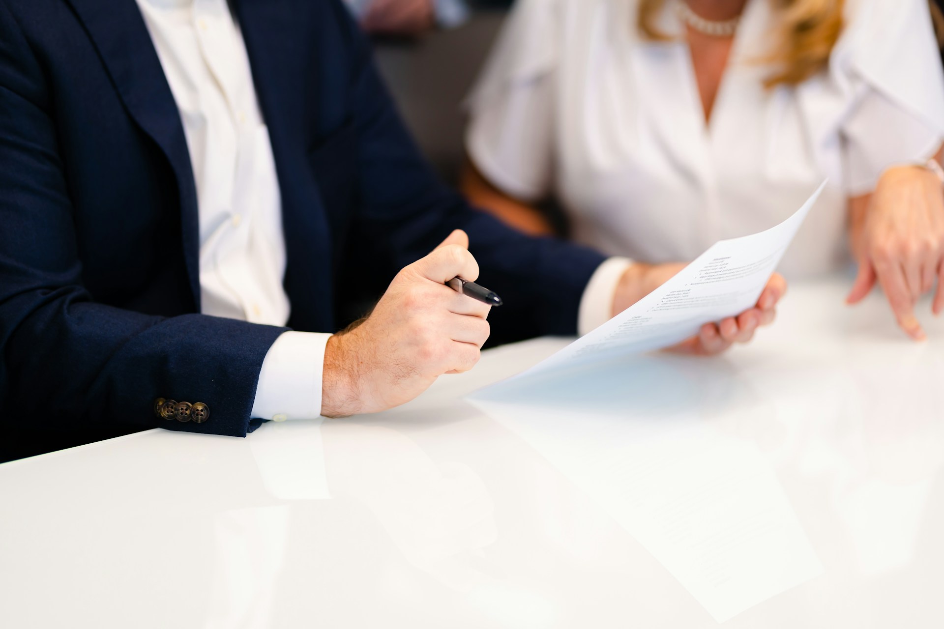 Business professionals reviewing and discussing a document at a meeting table, representing contract management, compliance and workplace procedures.