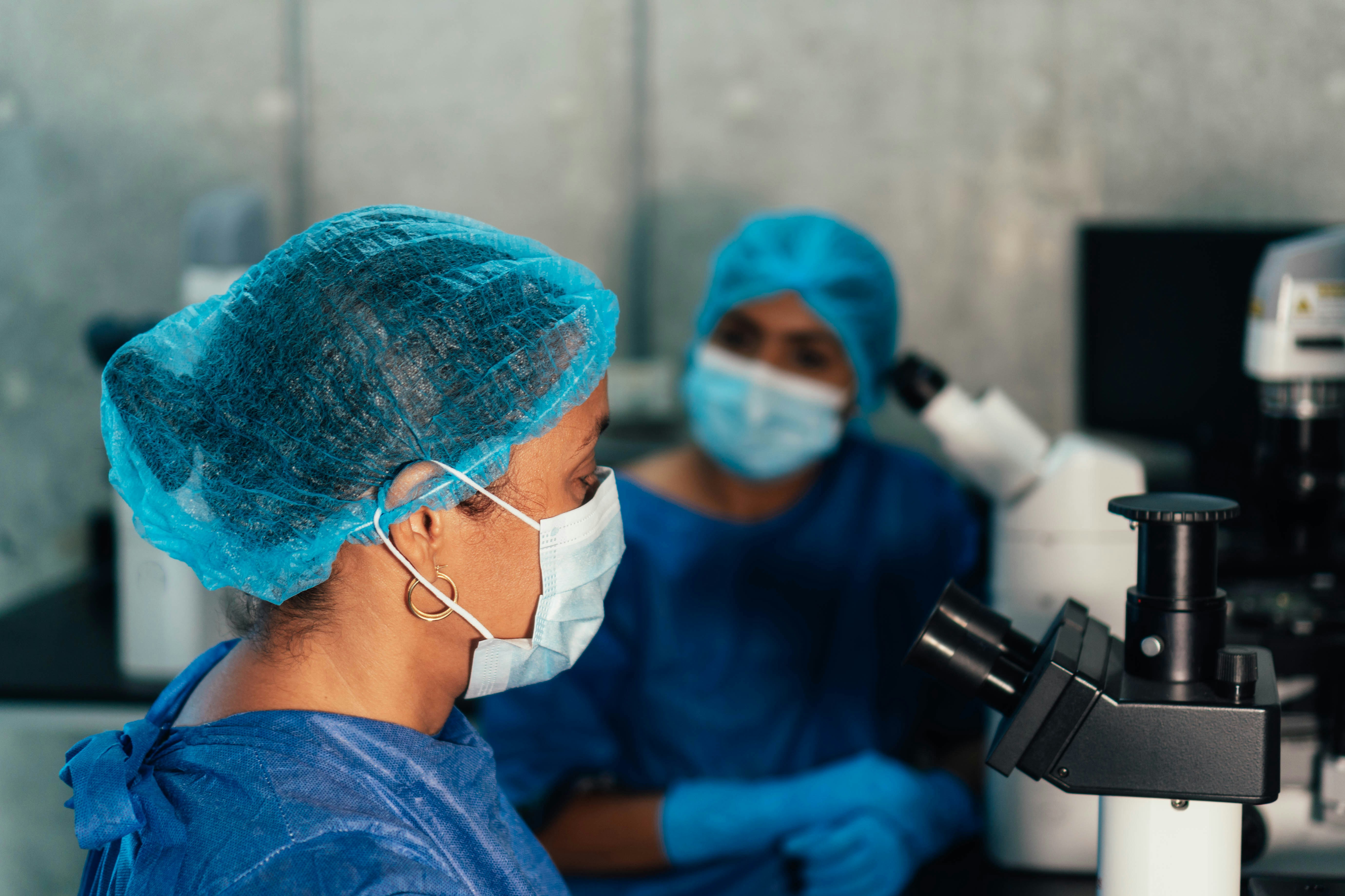 Researchers in a laboratory using microscopes and discussing scientific work, illustrating collaboration and innovation in the life sciences sector.