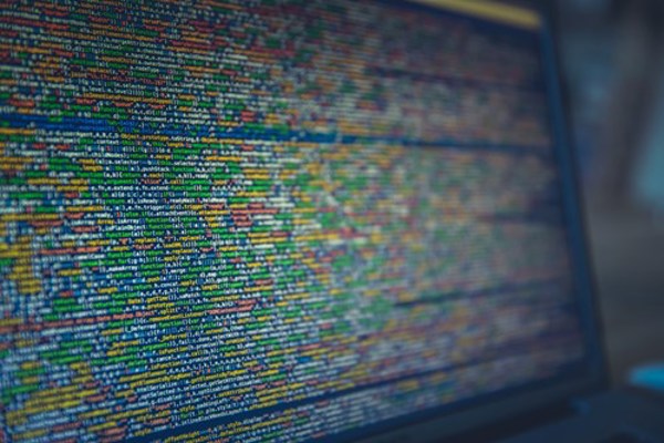 Laptop screen displaying blurred, colorful programming code.