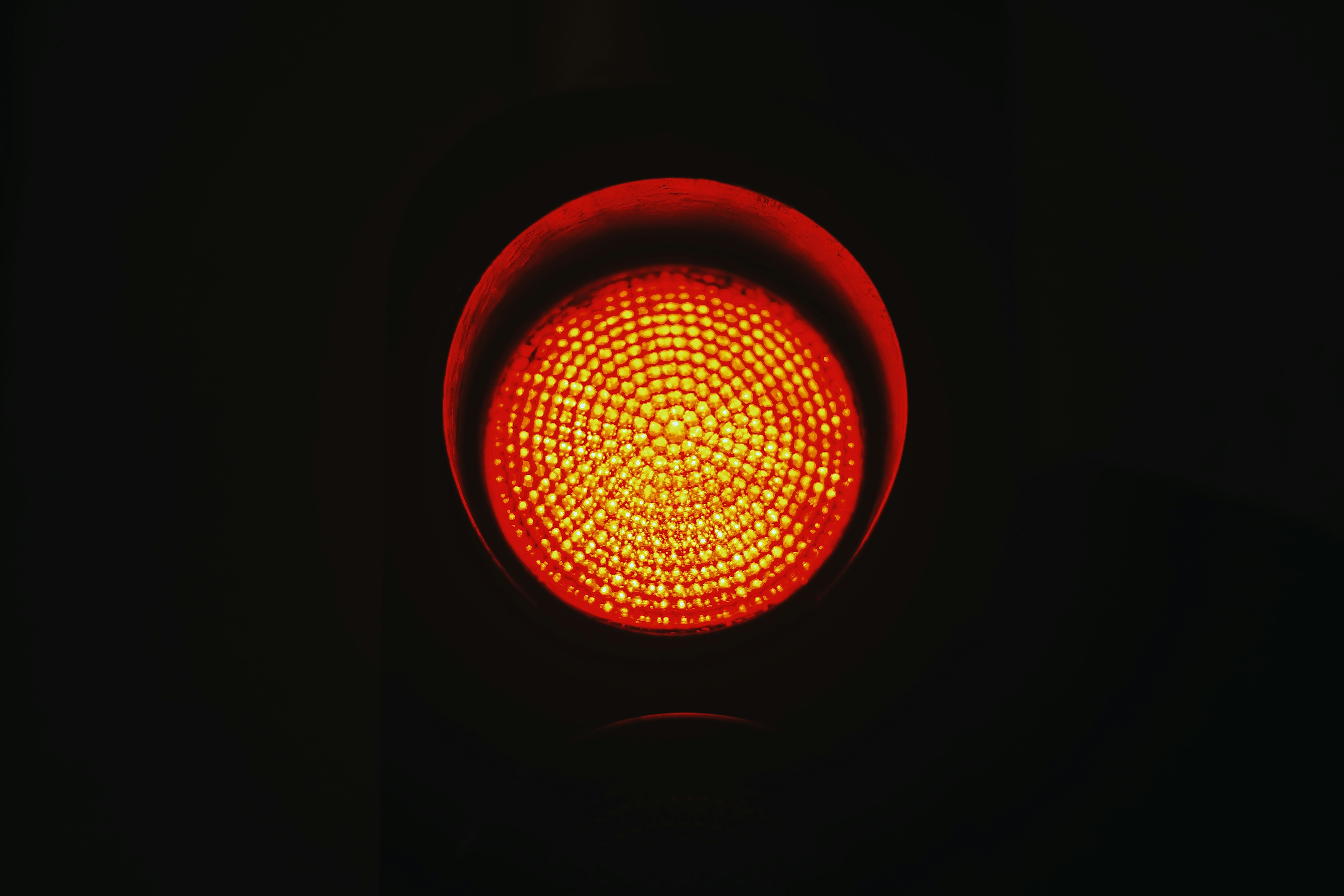 A close-up of a red traffic light illuminated against a dark background.