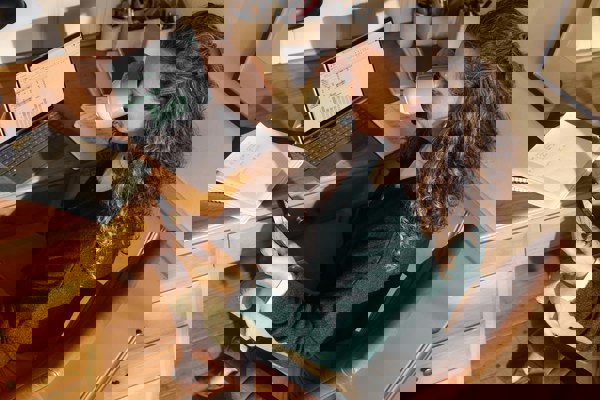 Person working at a home desk, reviewing documents alongside a laptop and work schedule, illustrating flexible working and remote work arrangements.