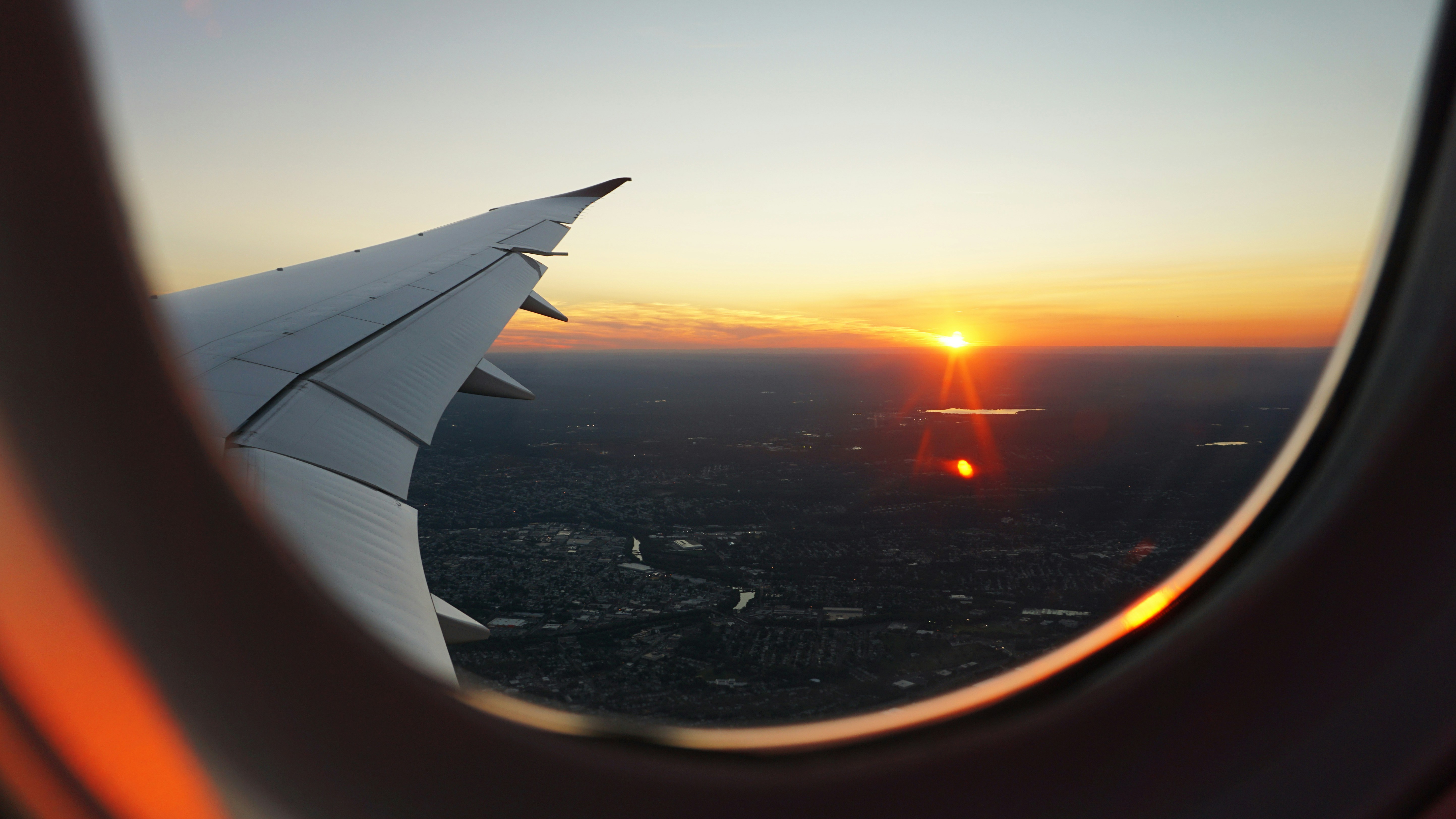 View from an aeroplane window showing a wing and the landscape below during a flight.